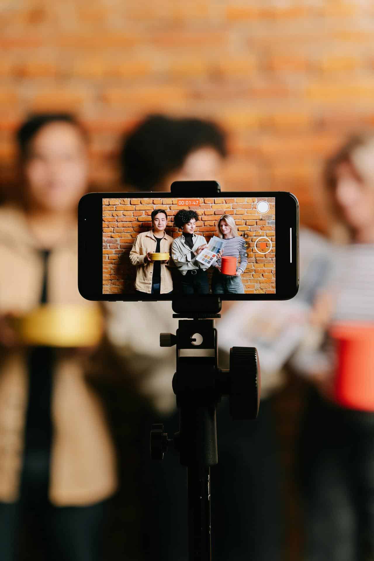 Friends celebrating joyfully with colorful props in front of a rustic brick wall.