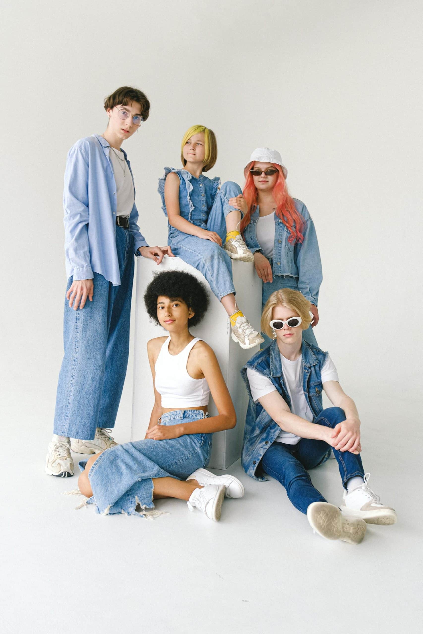 Five individuals showcase trendy denim styles in a bright, minimalistic setting.