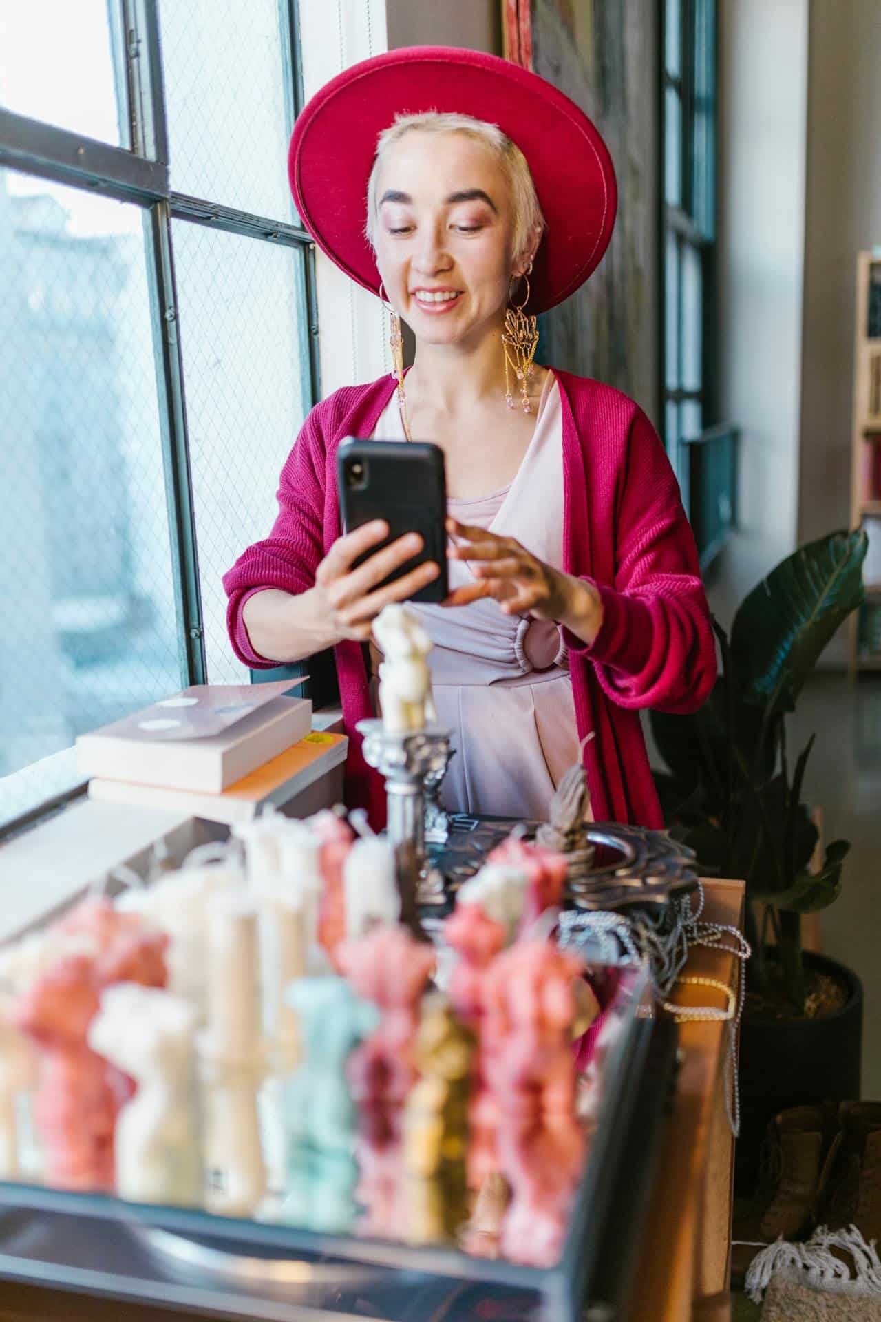 Chic woman photographing colorful candles in a bright, modern urban space.