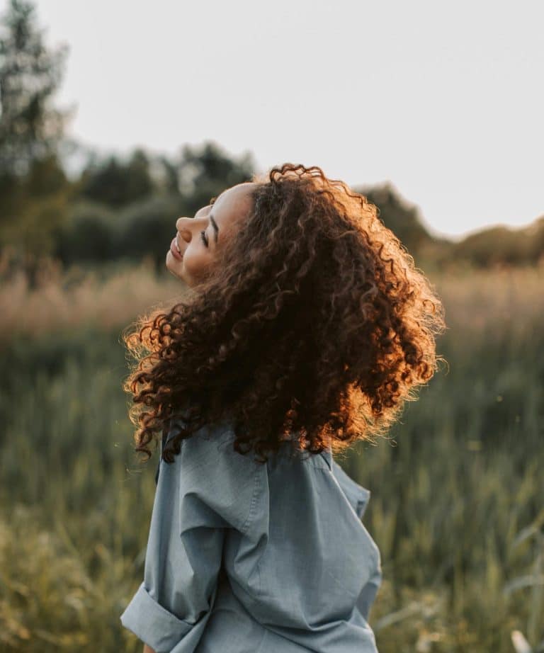 Joyful woman enjoying natures beauty in a sunlit field during golden hour.
