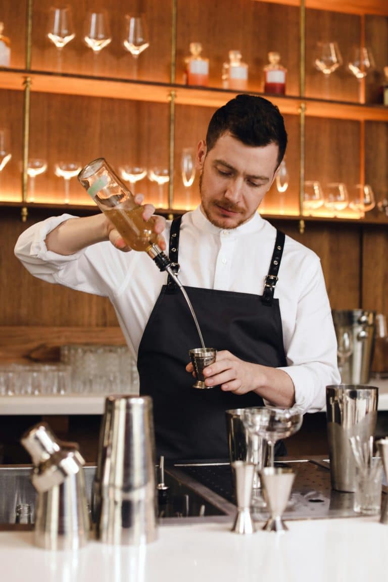 Skilled bartender crafting cocktails in a chic bar, showcasing mixology artistry and precision.