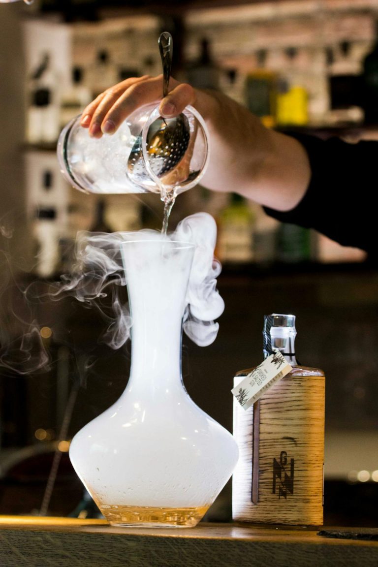 Skilled bartender creates a captivating cocktail, showcasing mixologys artistry in an inviting bar setting.