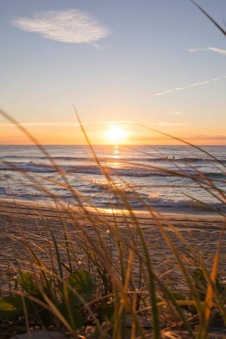 Tranquil beach sunset with golden waves and vibrant skies, perfect for a peaceful escape.