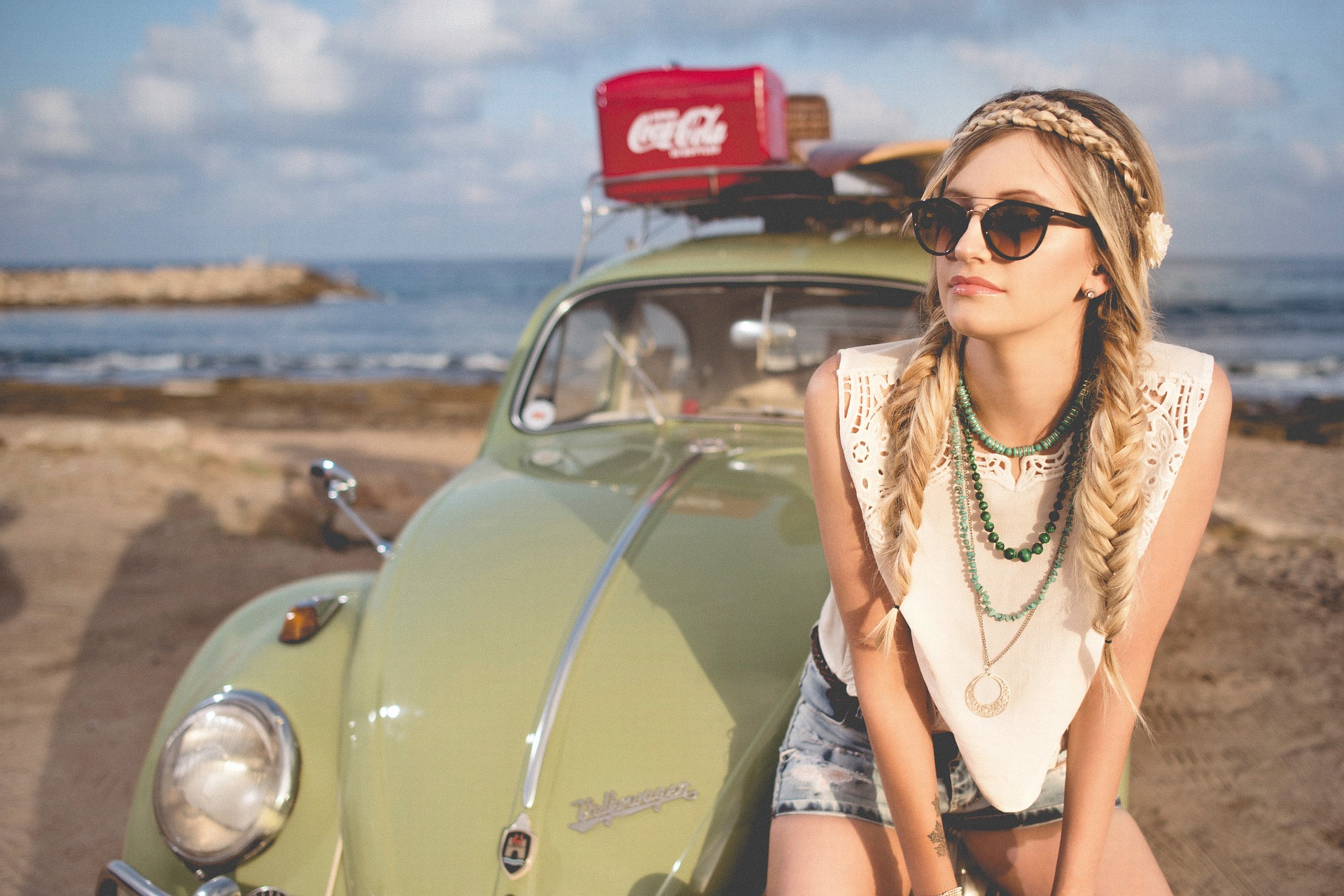 Summer beach scene with a vintage green Volkswagen Beetle and a bohemian woman ready for adventure.