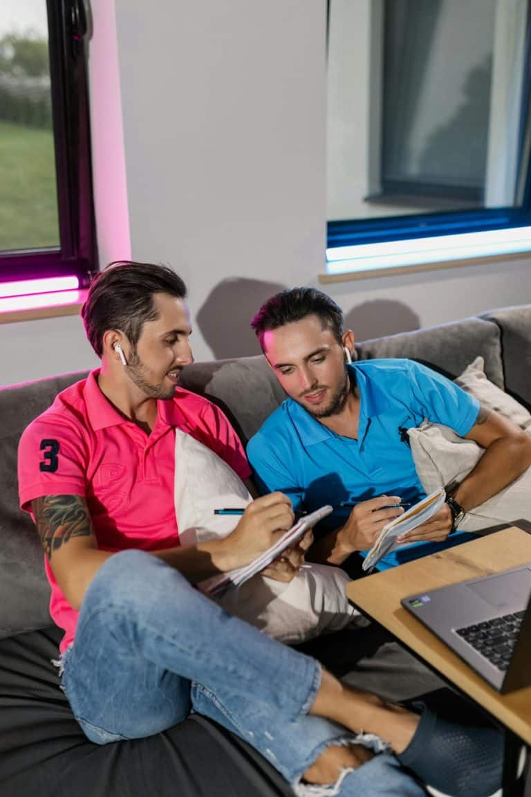 Two men writing together on a couch