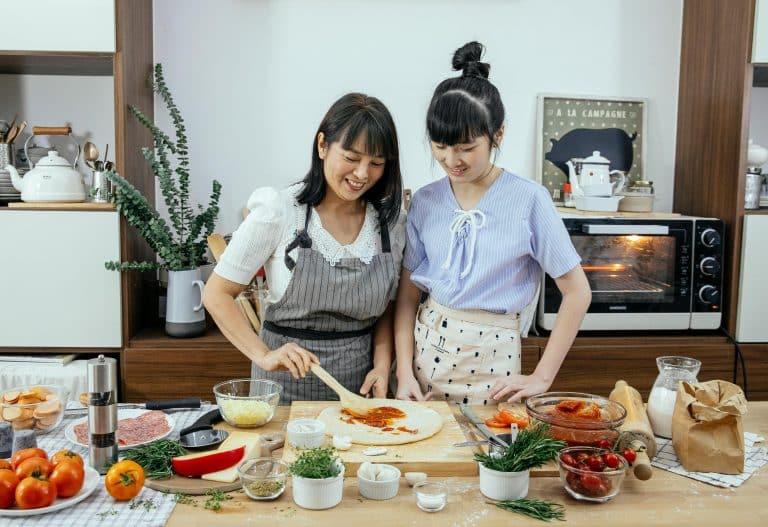 Two friends joyfully cooking together in a modern kitchen filled with fresh ingredients.