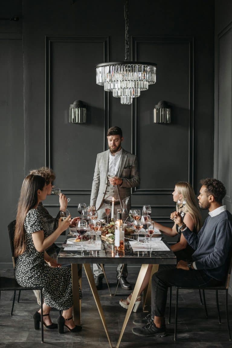 Sophisticated dining with friends, toasts, and gourmet food in an elegant, modern setting.