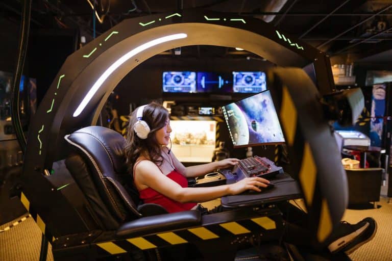Young woman immersed in a sleek gaming pod with vibrant displays and LED lighting.