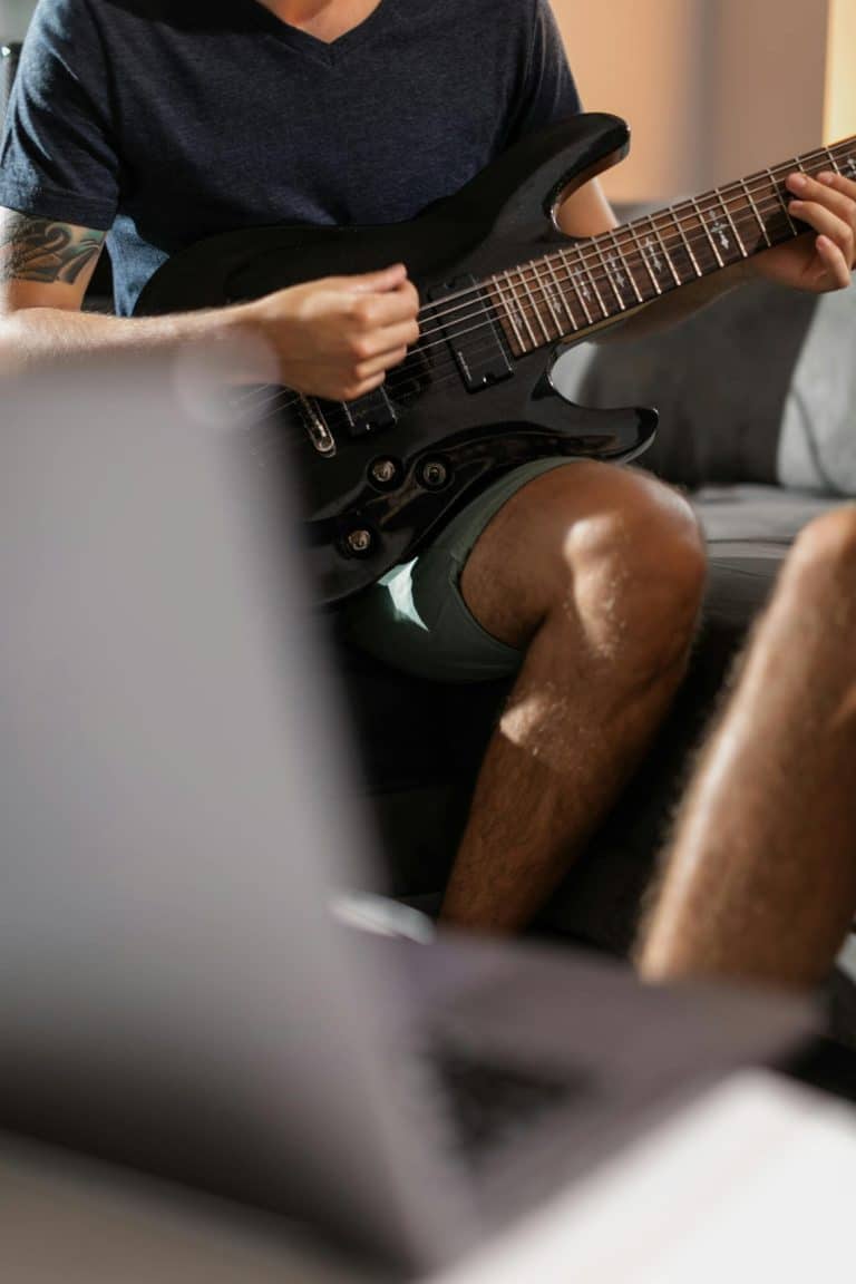 Person playing black electric guitar indoors
