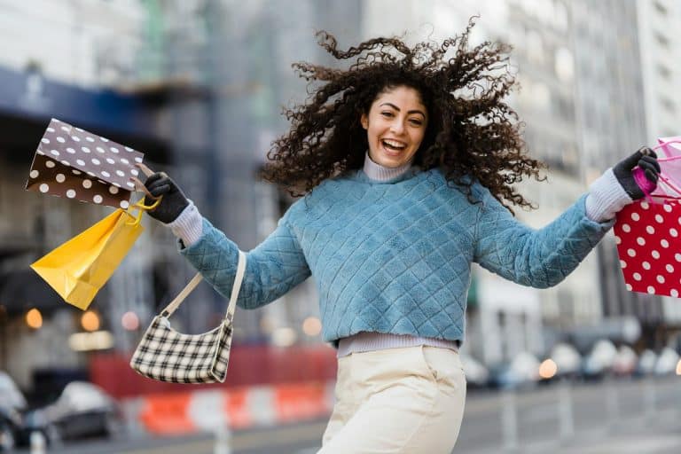 Joyful woman shopping in the city, carrying colorful bags and radiating happiness.