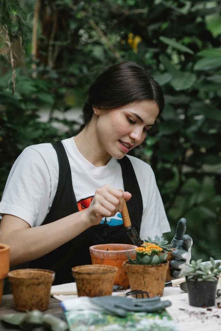 Young woman potting plants indoors, surrounded by greenery, showcasing her passion for gardening.