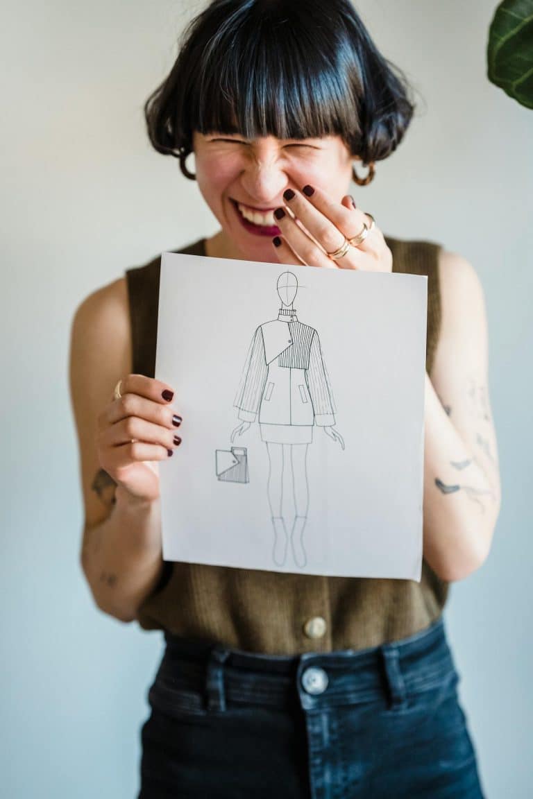 Joyful woman with blunt bob showcases her fashion illustration, exuding passion for design.