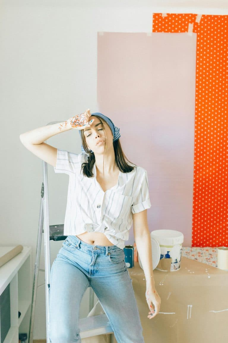 Creative young woman joyfully transforming her space with a colorful DIY project.