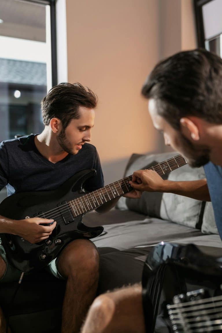 Two men practicing electric guitar together indoors