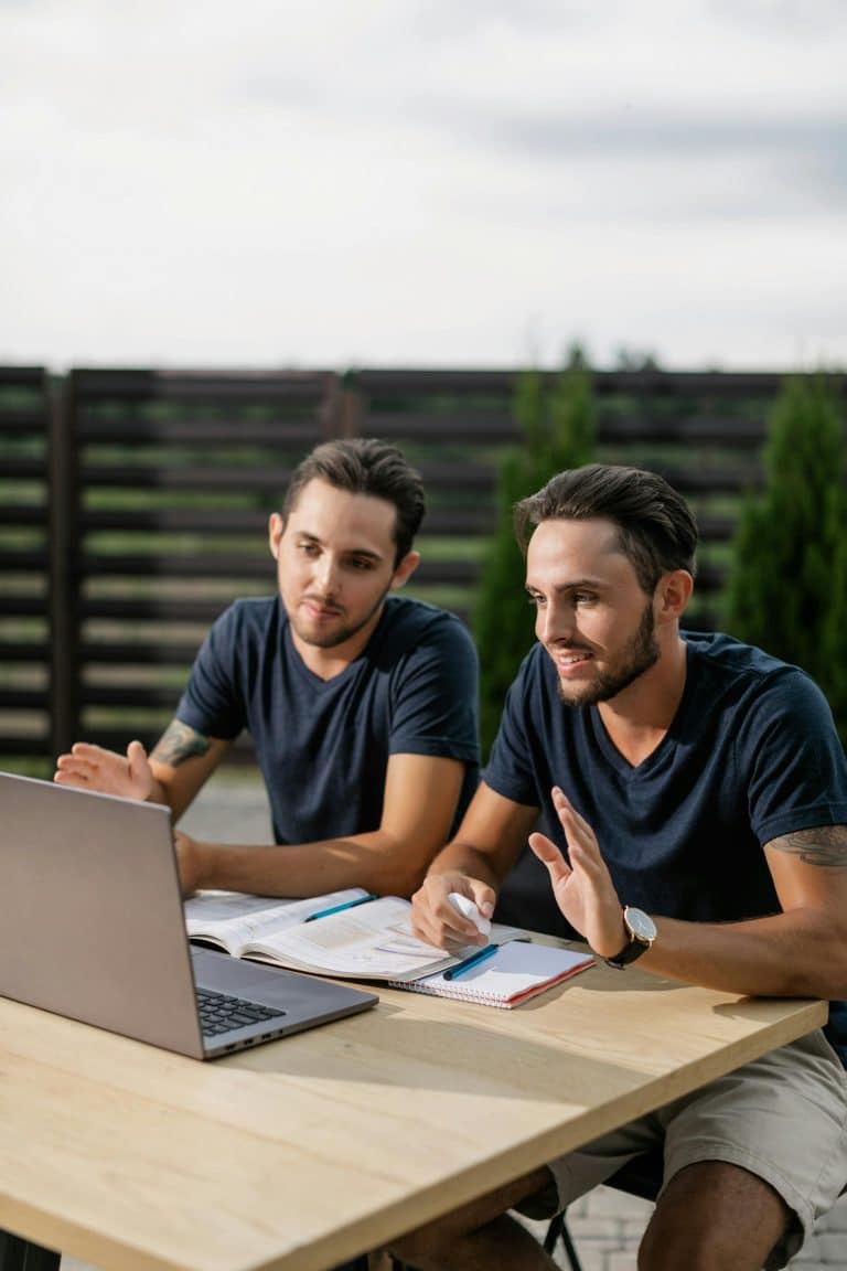 Two men studying together with a laptop outdoors