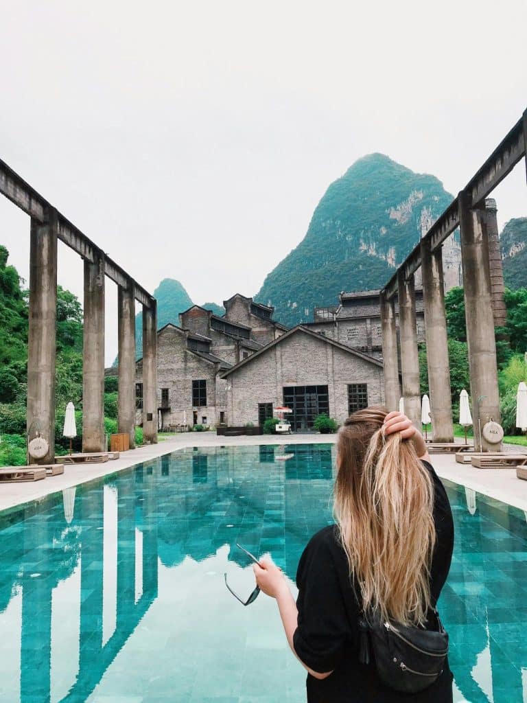 Reflective pool with mountains and rustic architecture, evoking tranquility and harmony.