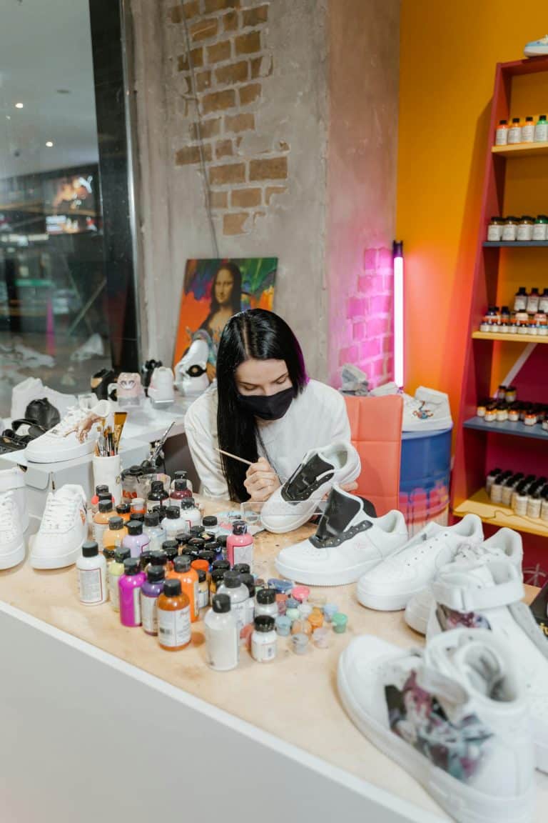 Creative shoe customization studio with an artist painting sneakers against a vibrant backdrop.