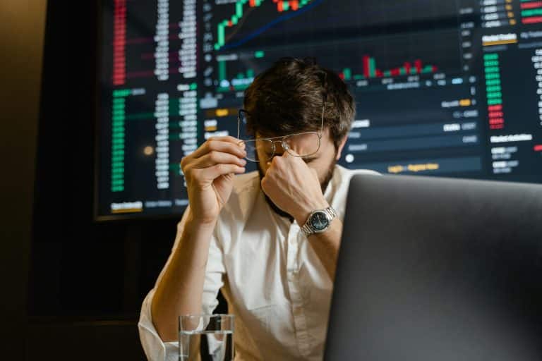 Young trader stressed by market data, analyzing financial charts in a high-pressure environment.