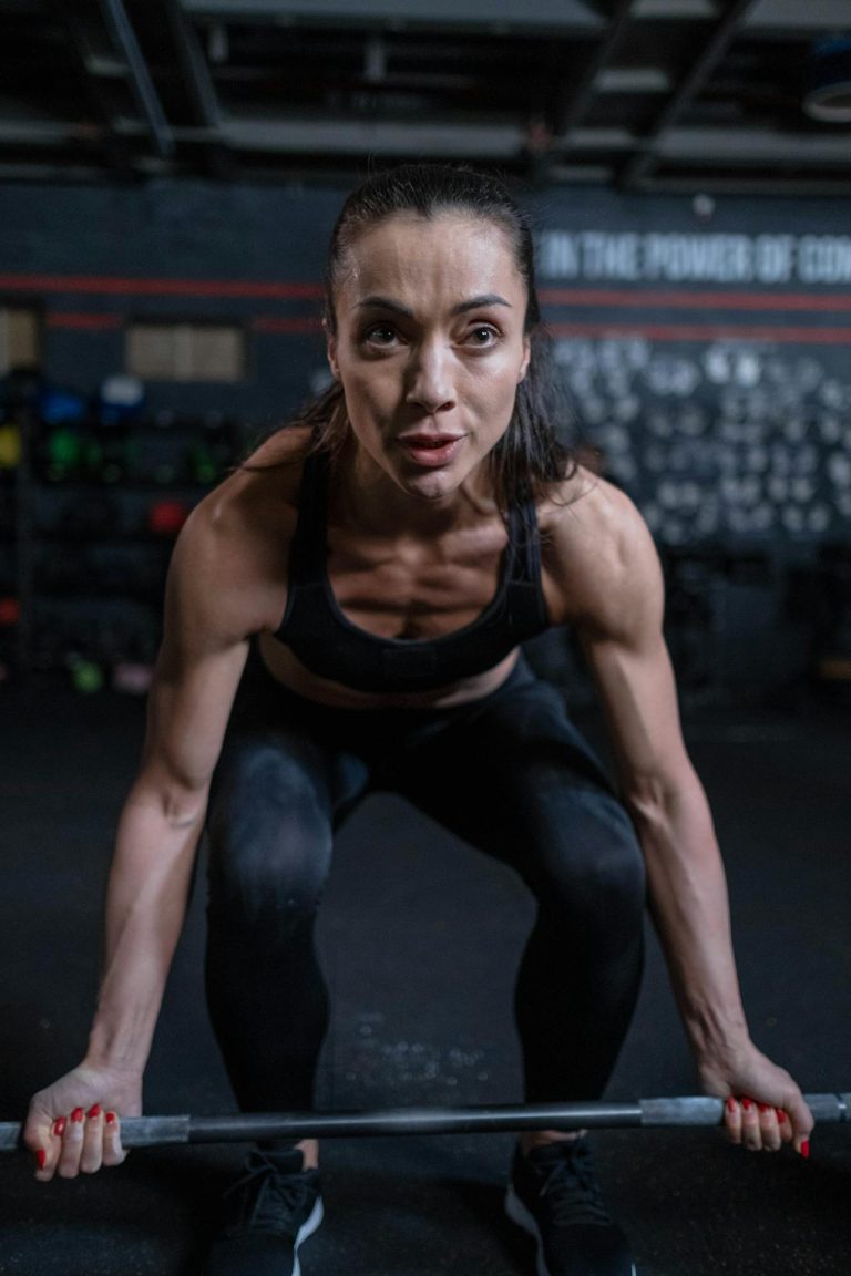 Athletic woman lifting weights, showcasing strength and determination in a gym setting.
