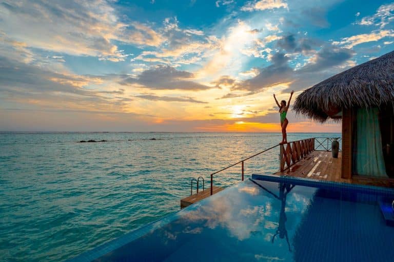 Joyful sunset celebration by the infinity pool and tranquil ocean in a tropical paradise.