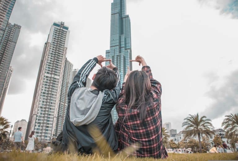 Friends enjoying city life together in front of a stunning skyscraper on a grassy area.