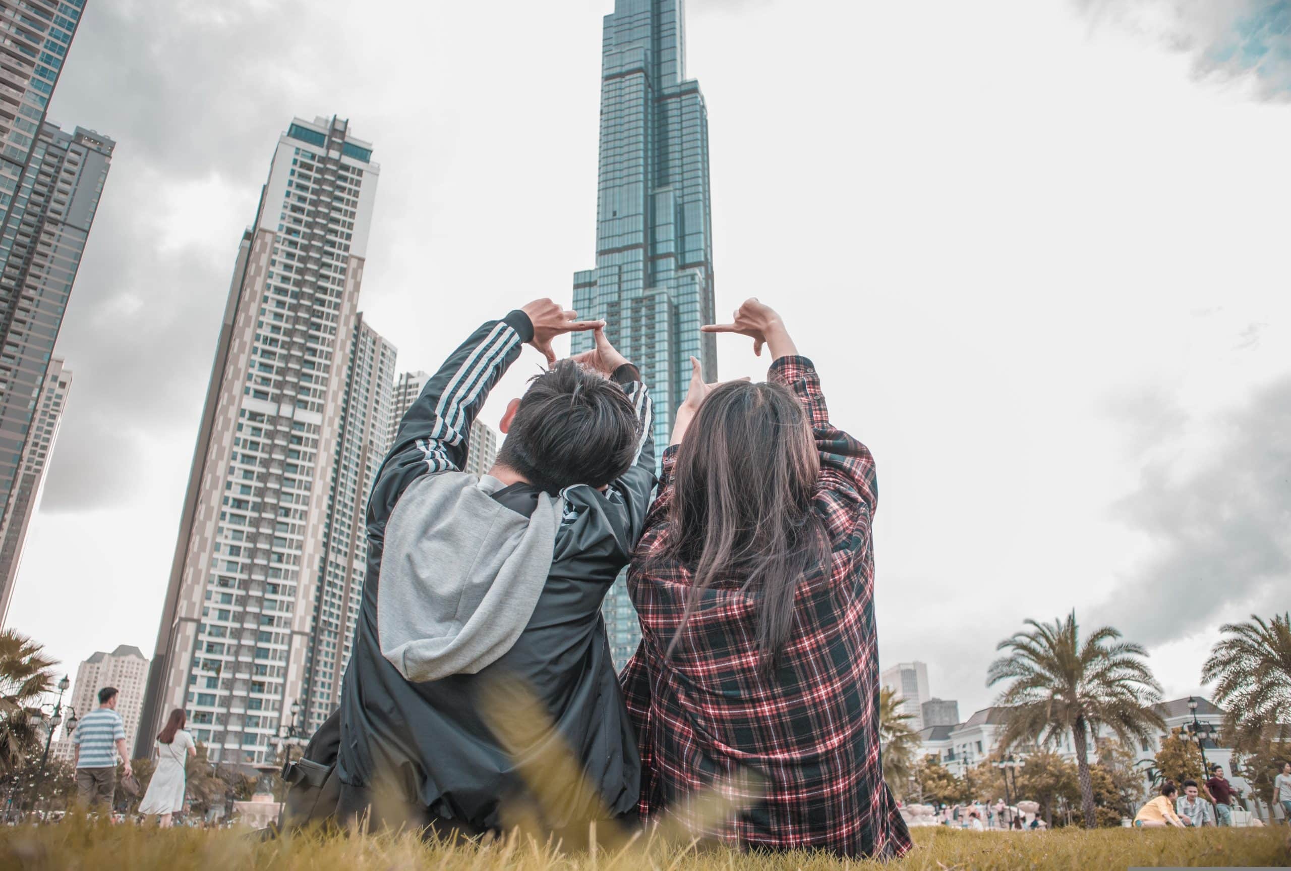 Friends enjoying city life together in front of a stunning skyscraper on a grassy area.