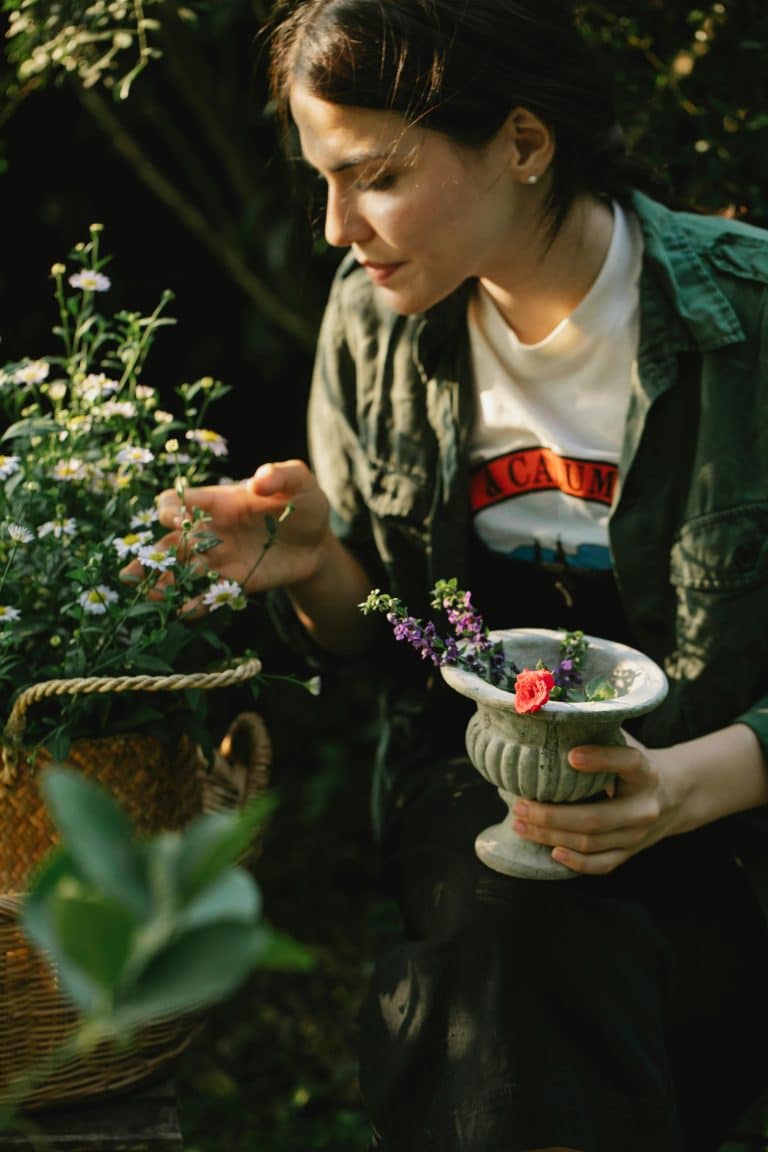 Woman gardening in a lush, vibrant garden, surrounded by colorful flowers and warm sunlight.