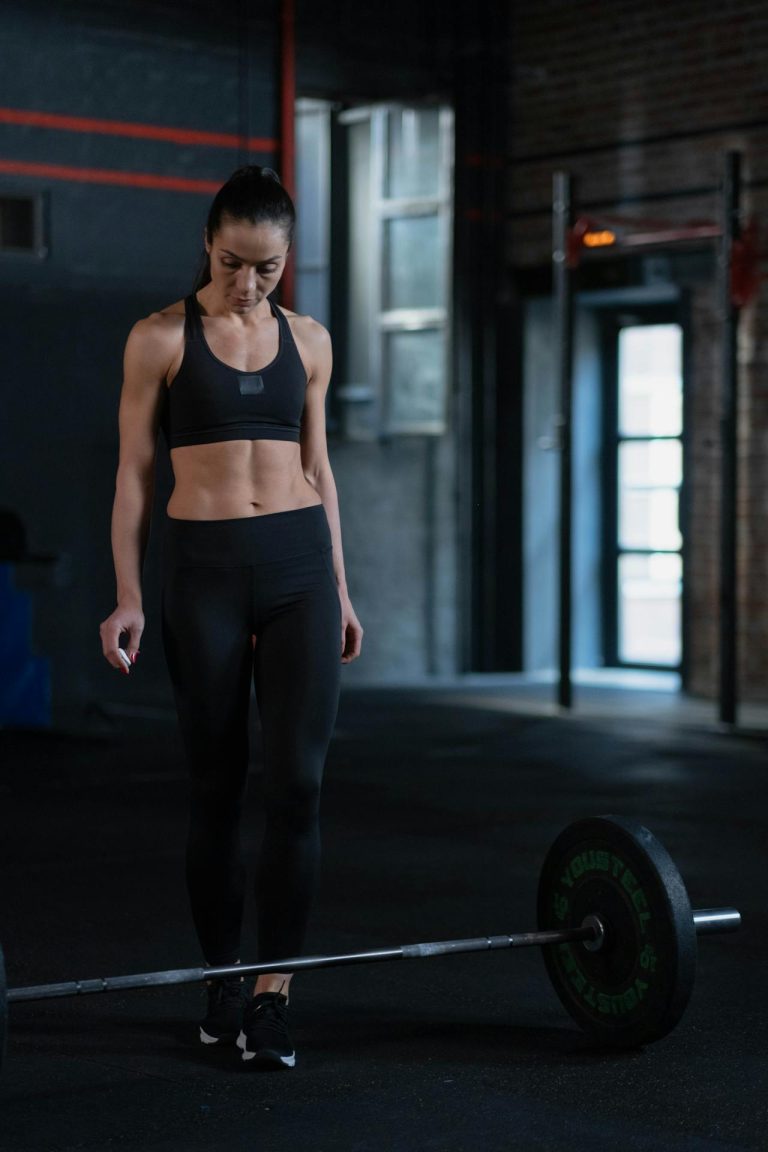 Focused woman prepares to lift a barbell in a modern gym, showcasing strength and determination.