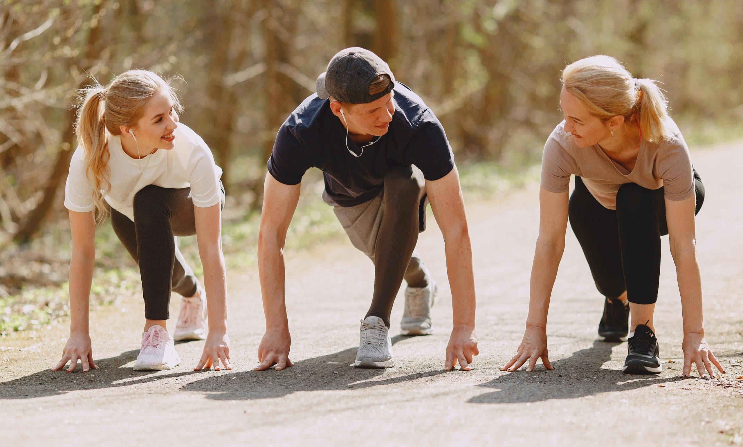 Three young adults ready to race outdoors, showcasing determination and camaraderie in nature.