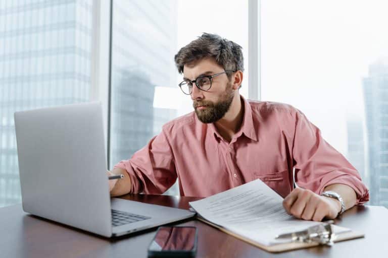 Young professional in a casual pink shirt working diligently at a sleek modern desk.