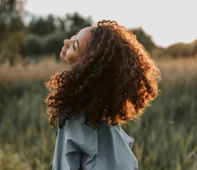 Joyful woman enjoying natures beauty in a sunlit field during golden hour.