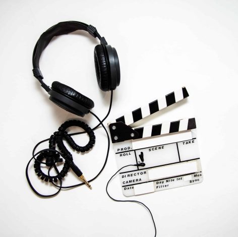 Black headphones and clapperboard symbolize the fusion of audio and visual storytelling in filmmaking.