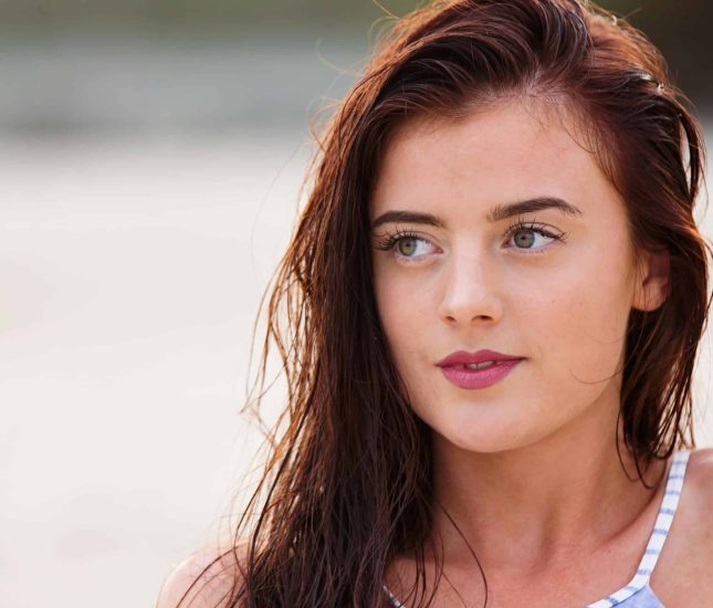 Young woman by the beach embodies tranquility and natural beauty in warm summer sunlight.