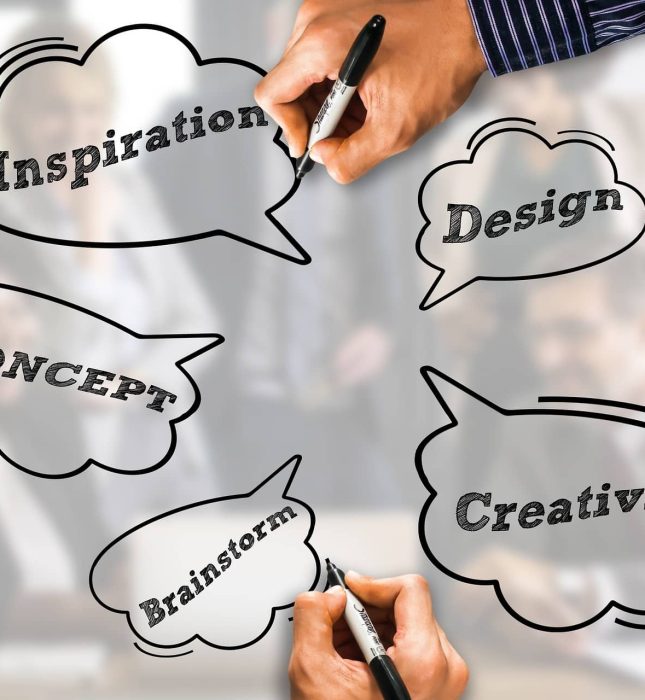 Collaborative brainstorming session with hands, markers, and key creative concepts in speech bubbles.