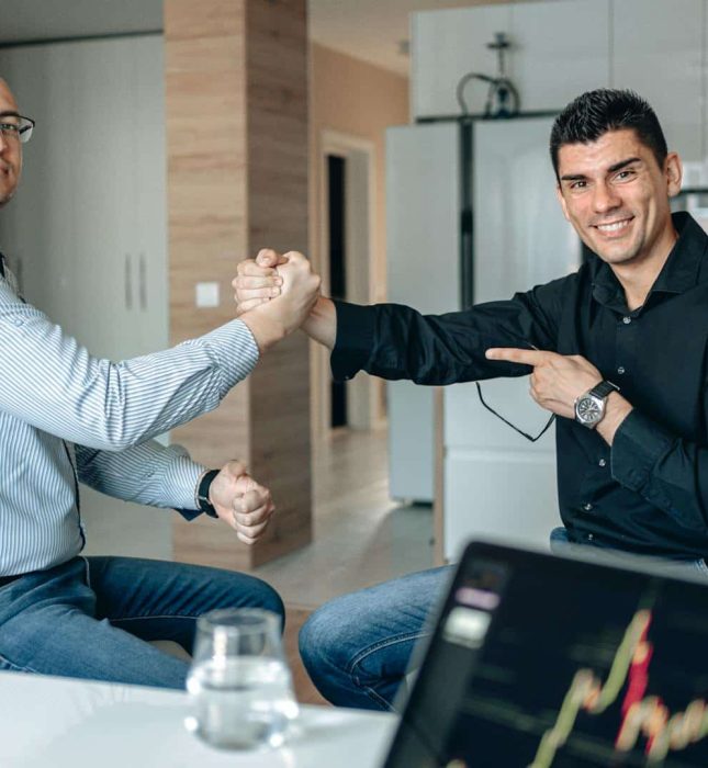 Playful arm wrestling challenge during a business meeting in a modern conference room.