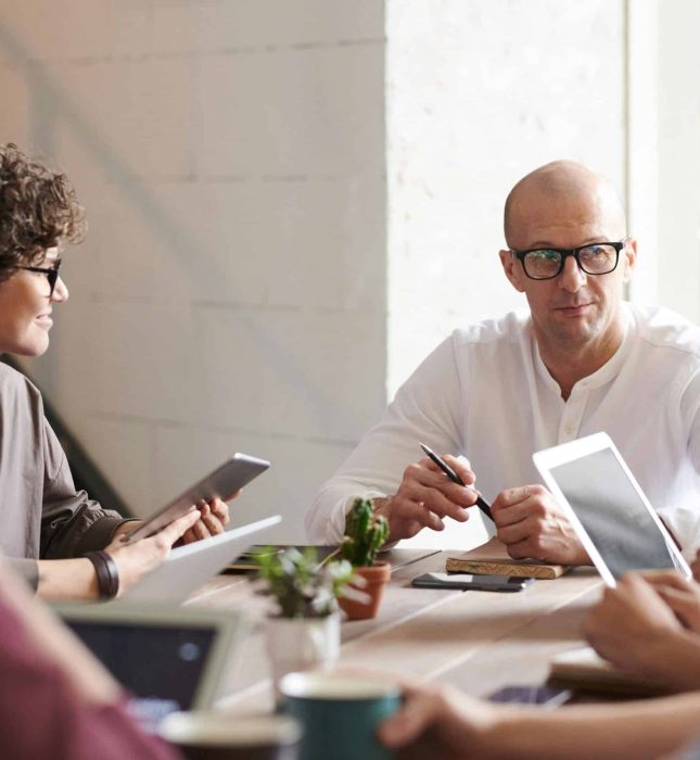 Engaged professionals collaborate in a bright, modern meeting space with technology and greenery.