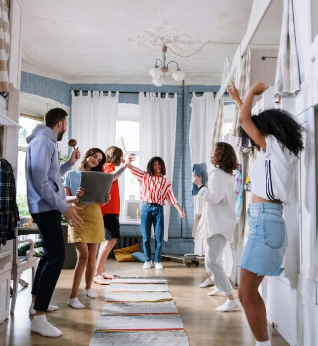 Vibrant gathering of friends dancing and celebrating in a bright, inviting space.