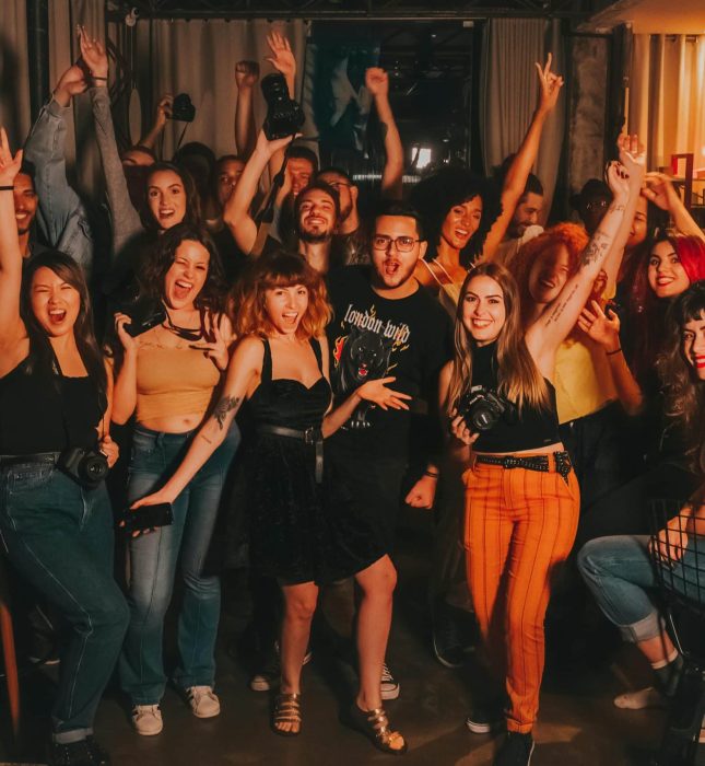 Young adults joyfully celebrate friendship in a cozy bar, showcasing vibrant fashion and smiles.