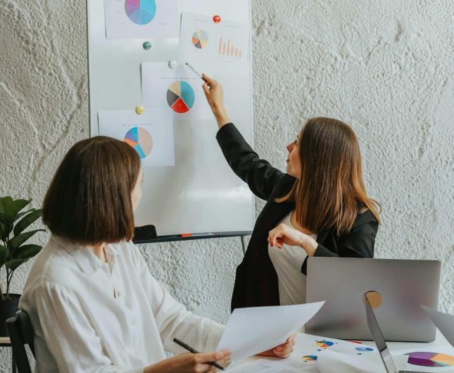 Women collaborating in a modern office, discussing charts and ideas with focus and confidence.