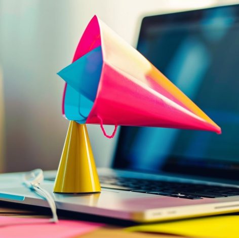 Vibrant megaphone on laptop symbolizes creativity and communication in a cozy workspace.