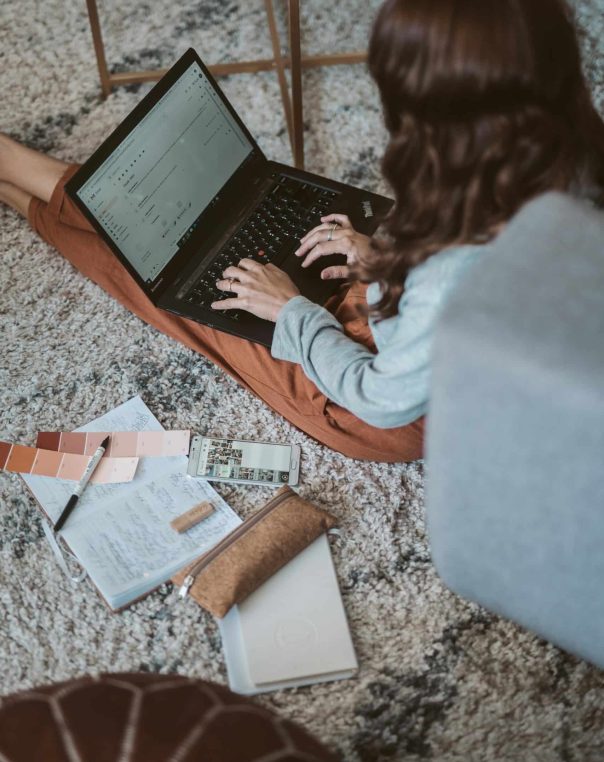 Cozy workspace featuring a person using a laptop surrounded by color swatches and creative materials.