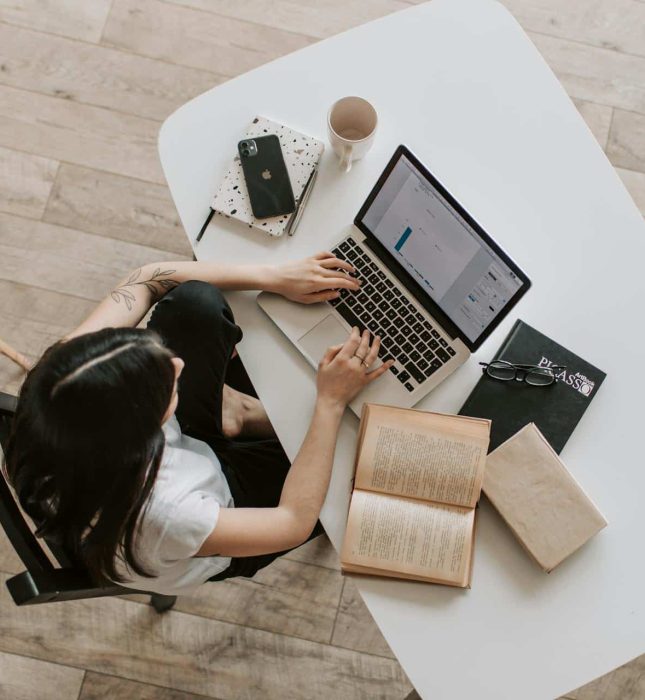 Cozy productivity workspace with laptop, books, and natural light for relaxation and creativity.