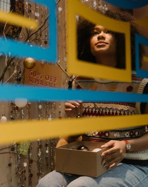 Young artist in vibrant studio reflects on creative project amidst colorful decorations.