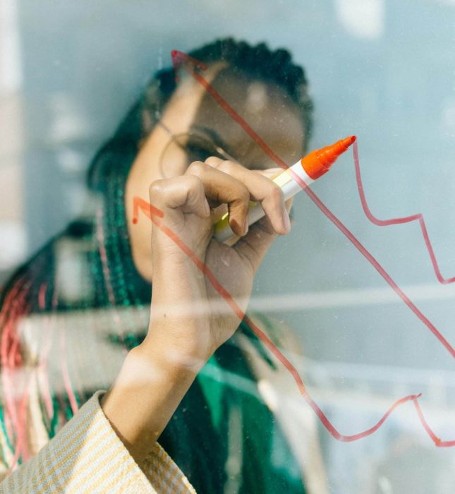 Person illustrating graphs with a red marker in a modern collaborative workspace.