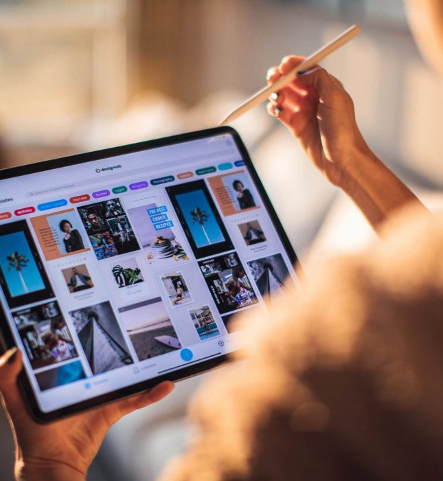 Artist creating digital art on a tablet, surrounded by inspiring design ideas in warm light.