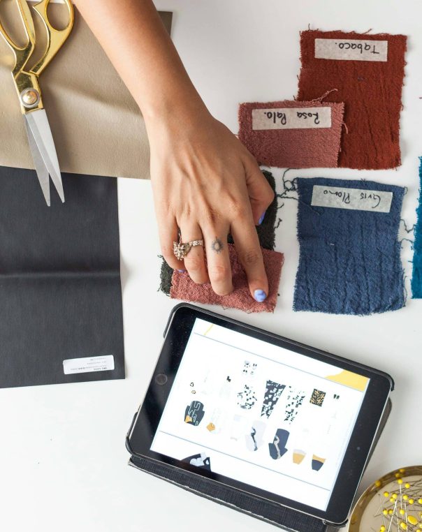 Vibrant creative workspace with digital designs, fabric swatches, tools, and embellishments for crafting.