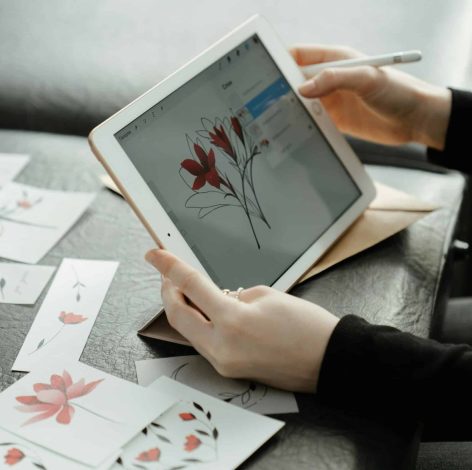 Person digitally illustrating flowers on a tablet in a cozy, inspiring workspace.