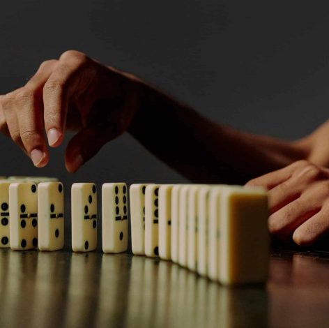 Hand reaching for dominoes, capturing the anticipation of a strategic game moment.