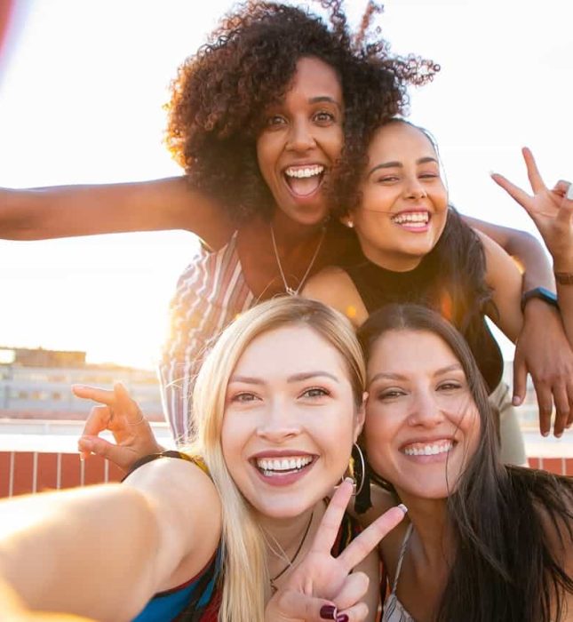 Friends enjoying a joyful rooftop selfie, radiating happiness and friendship under a sunny sky.