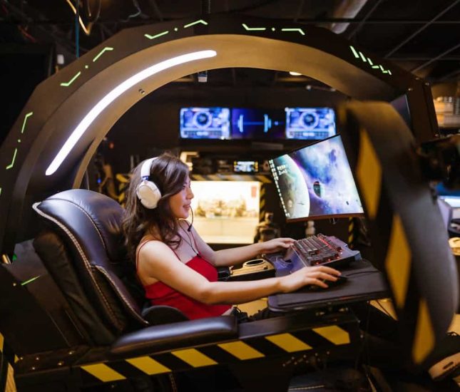 Young woman immersed in a sleek gaming pod with vibrant displays and LED lighting.